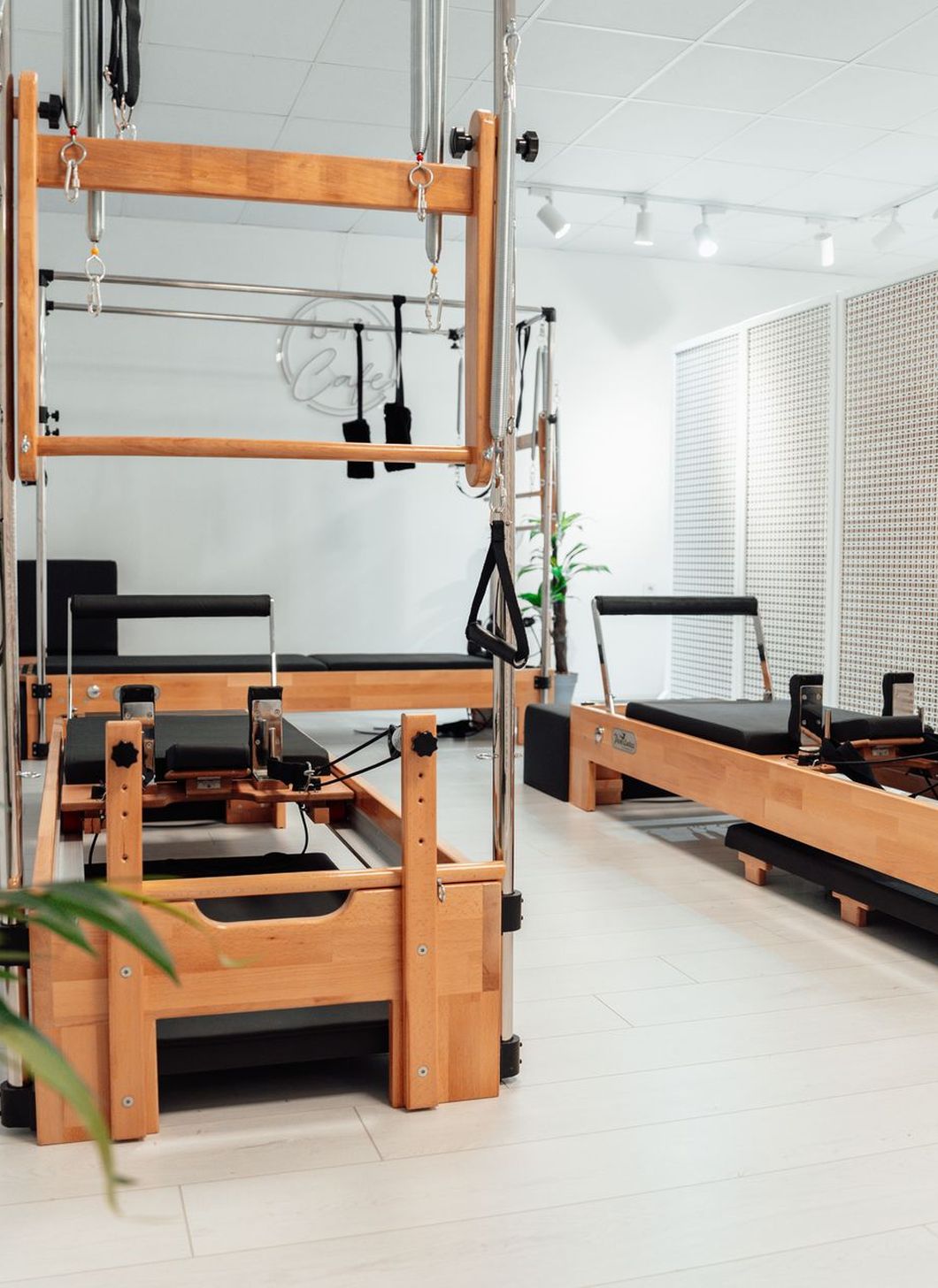 Studio de Pilates clair équipé d'un Cadillac et de Reformers en bois.