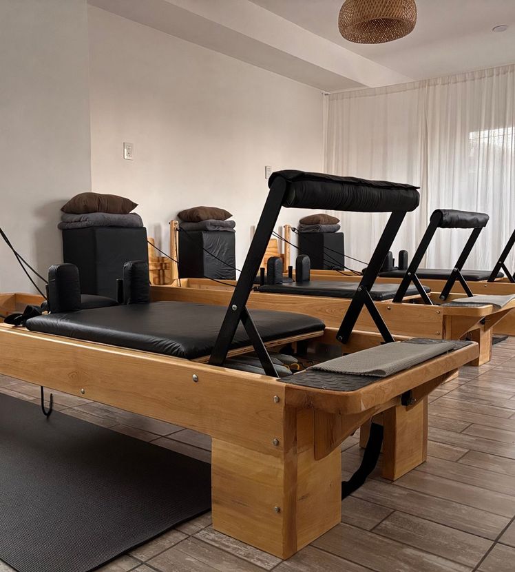 Salle de Pilates spacieuse aux Reformers en bois.