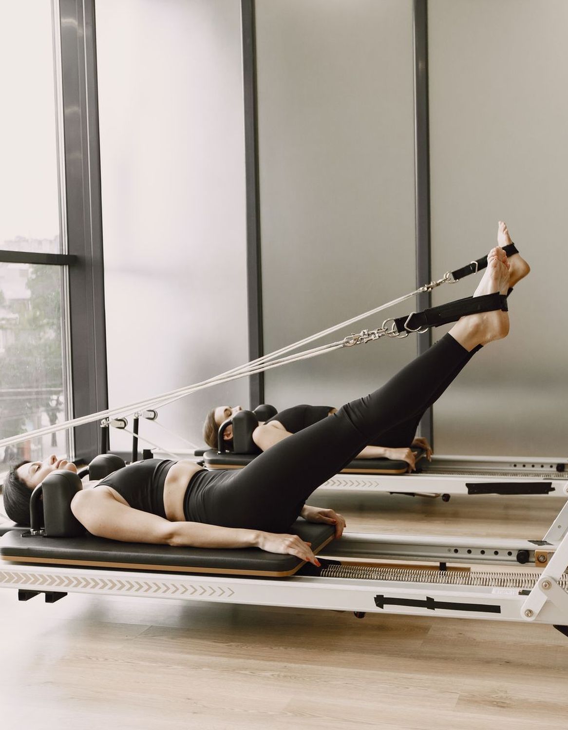Une élève en séance de Pilates sur Reformer dans un studio clair.
