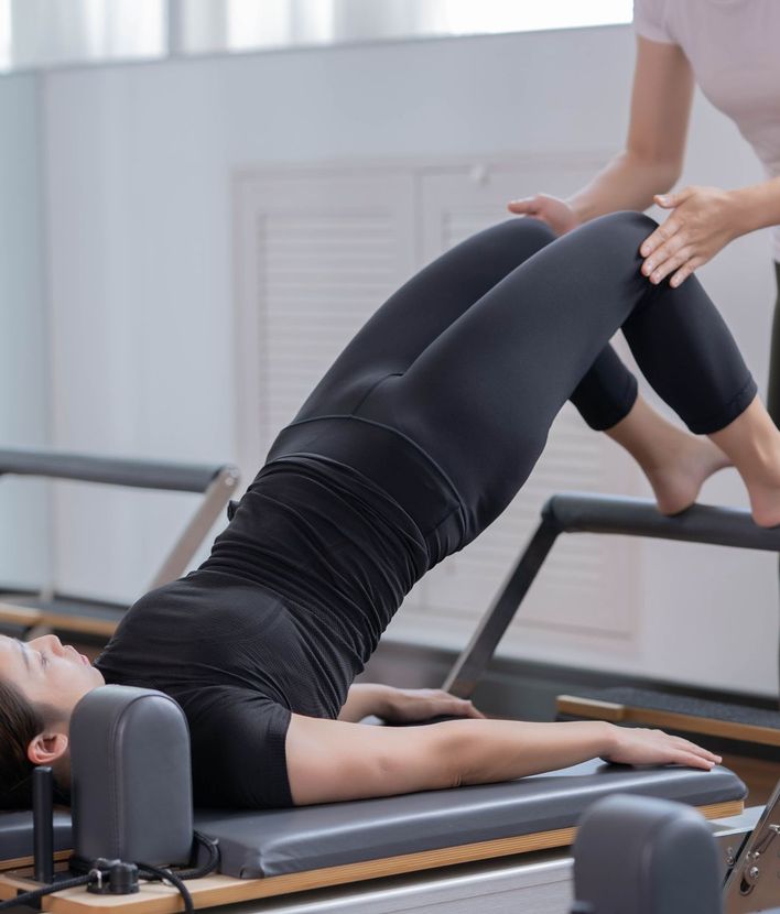 Une élève en séance de Pilates sur Reformer, accompagnée par sa professeure.